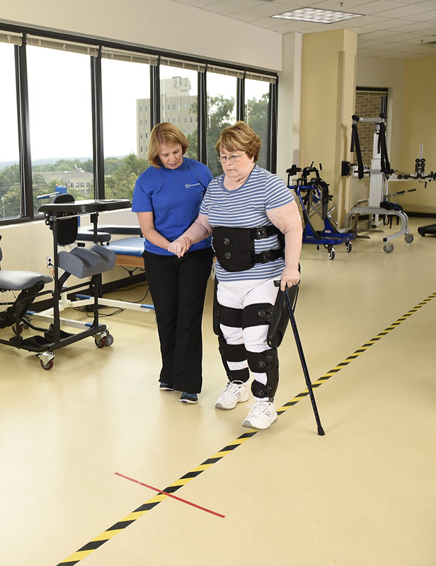 personne âgée qui marche avec l'exosquelette et une canne