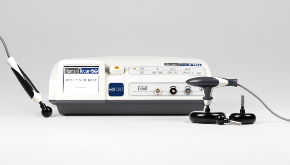 Appareil de tecarthérapie Human Tecar HCR 1002 avec ses électrodes Hydra Fascia (pièces à main) de traitement. Unité centrale grise et noire sur fond gris clair. Équipement médical ou de physiothérapie haut de gamme.
